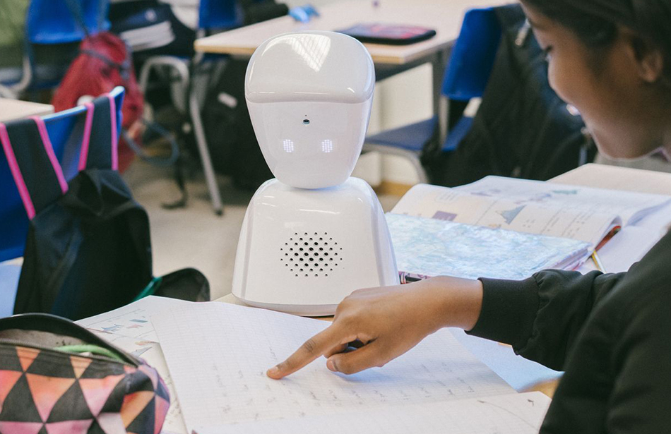 small robot looking down at schoolwork on desktop