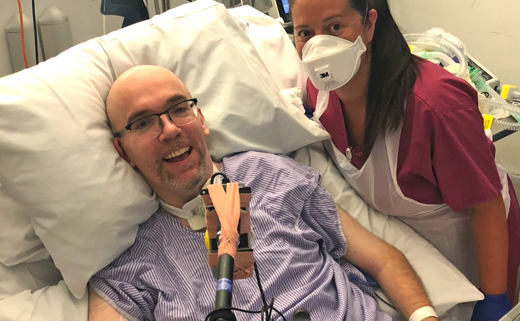 Smiling man in hospital bed with nursing sister standing