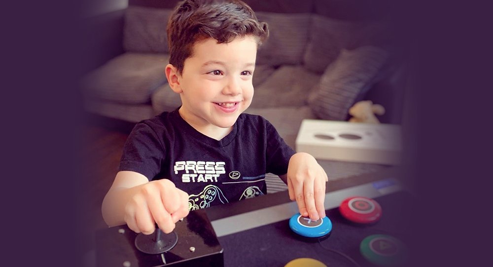 smiling young boy pressing large assistive gaming button