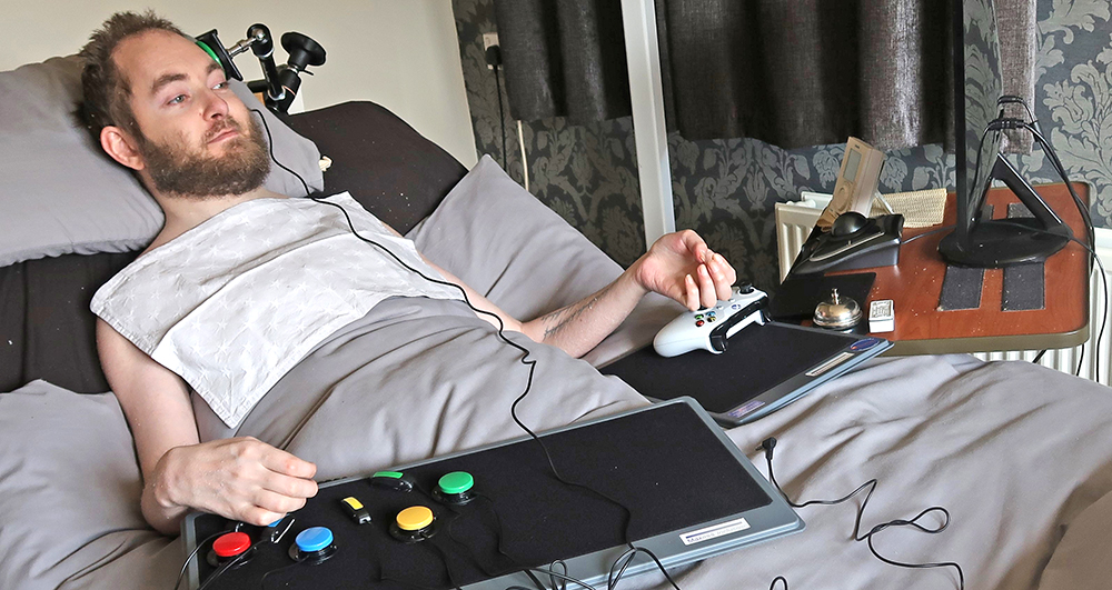 Man lyin in bed using games controller and button switches