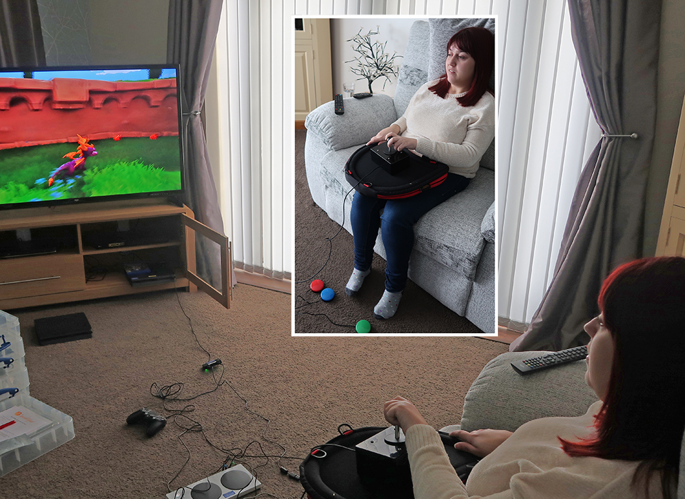 Woman sirring on sofa using large gaming joystick and foot buttons
