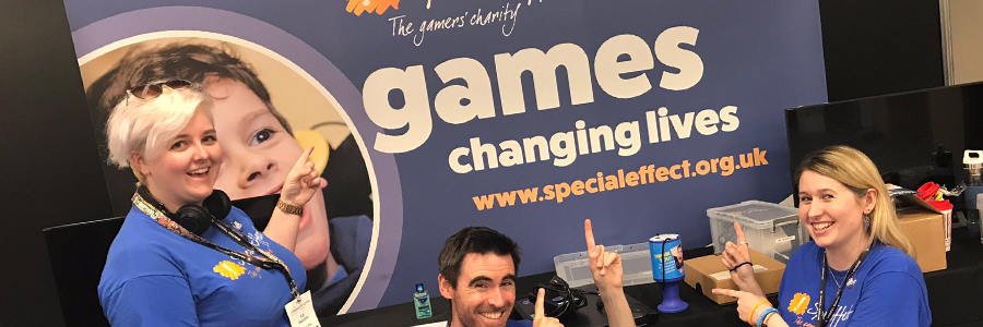 three smiling people pointing to SpecialEffect exhibition stand