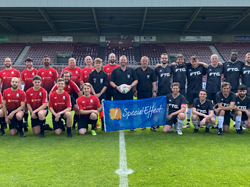 Two football teams with charity banner