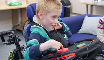 Boy in wheelchair using adapted gaming controls