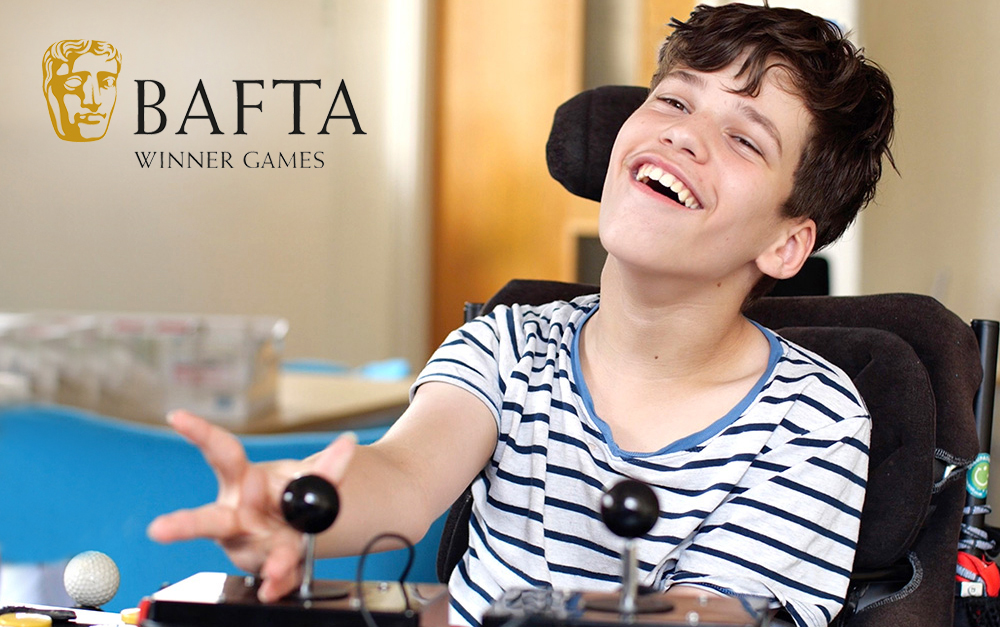 Smiling young man reaches for adapted gaming joystick