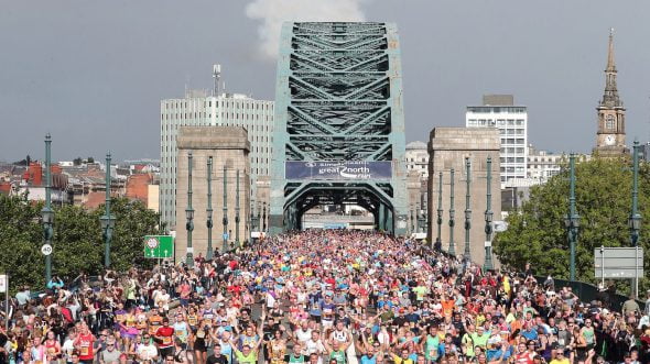 Thousands of runners crossing a bridge