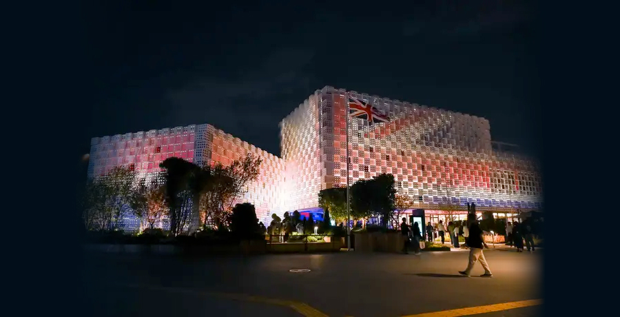 Night shot of two large modern cube-shaped building lit with a UK flag